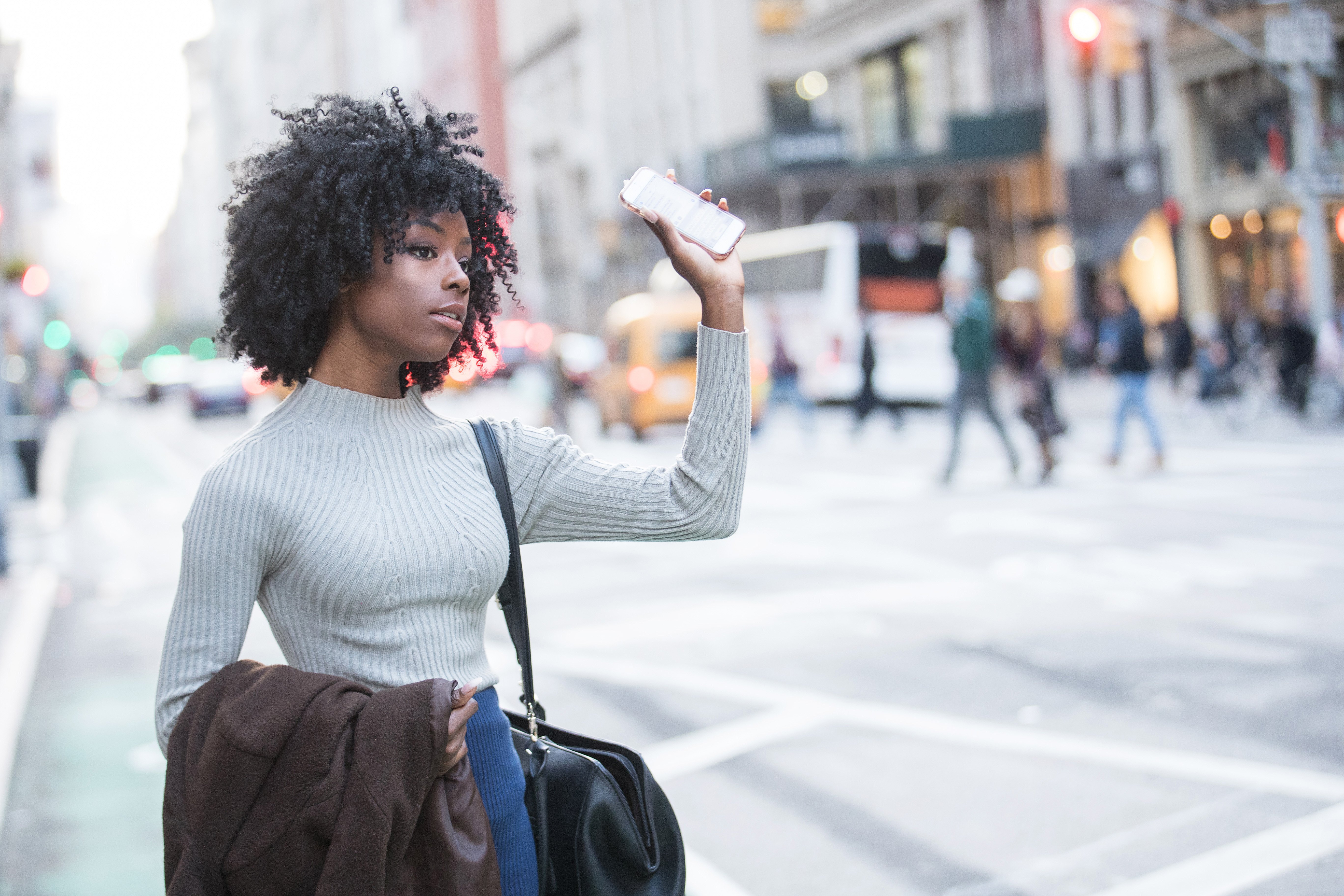 An image of a woman who has just called a rideshare on her phone.