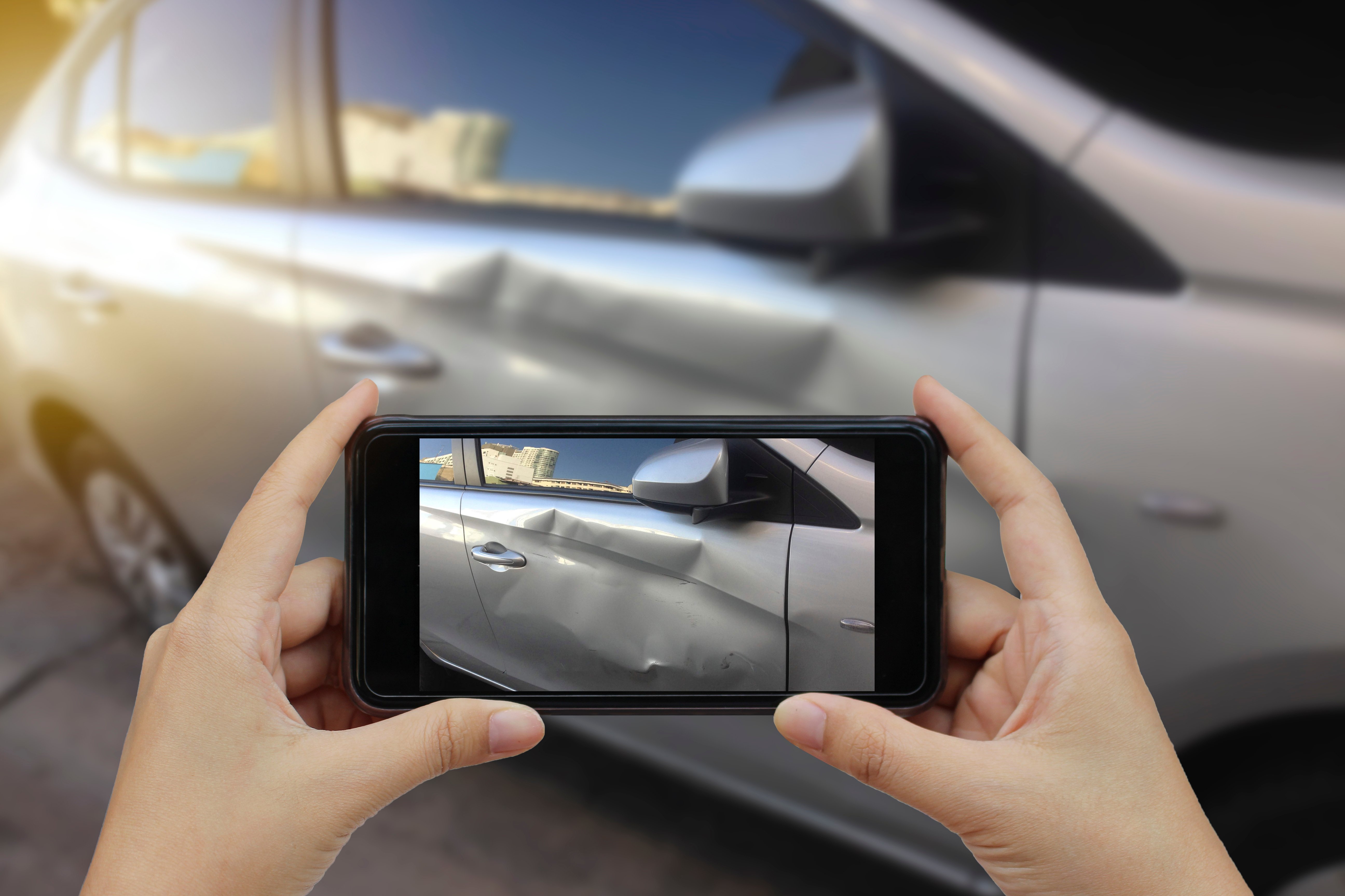 An image of a person taking photo evidence of a car accident.