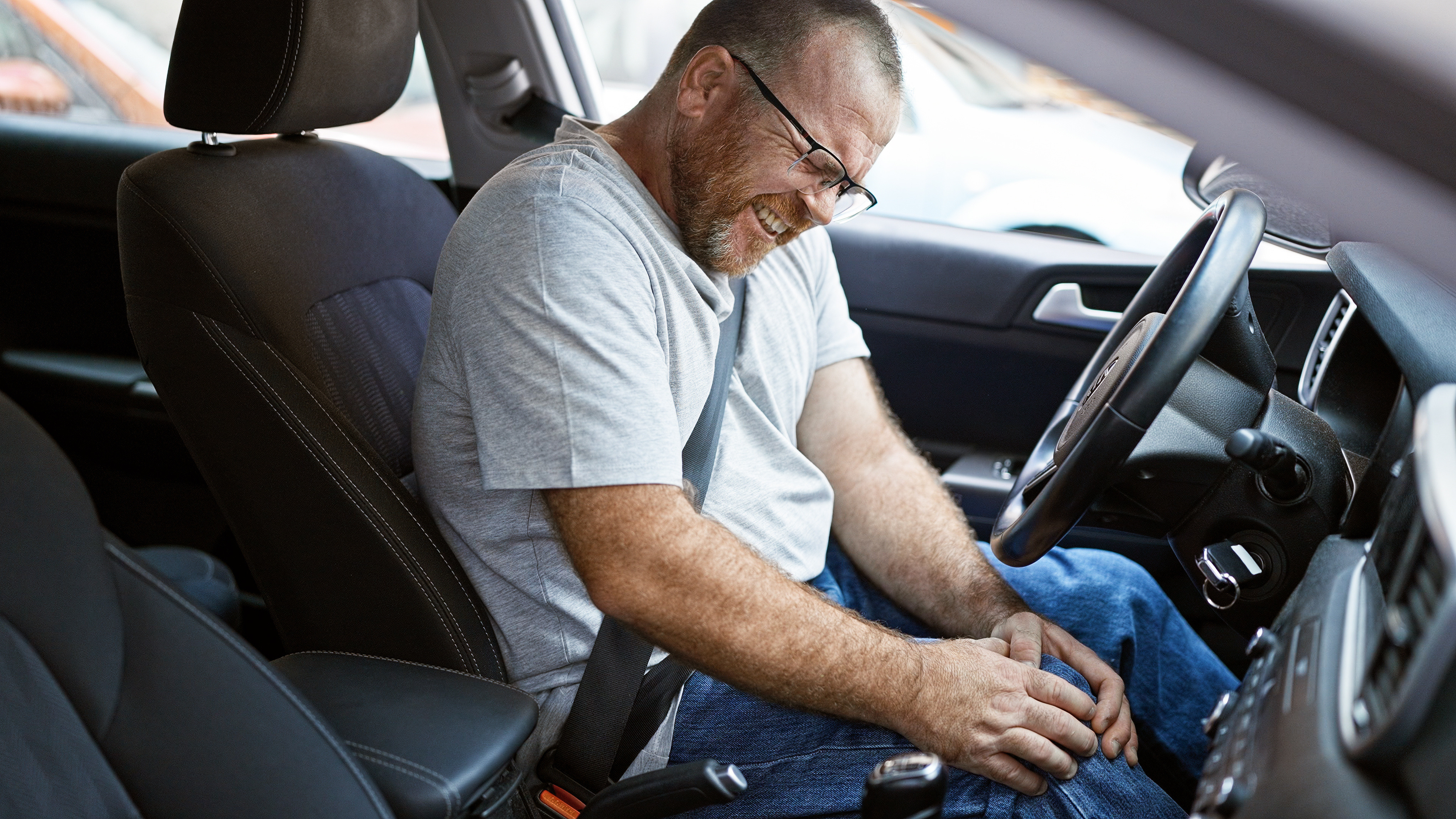 An image of a man holding his knee, wondering what to do after a car accident not his fault.