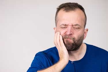 man holding mouth in pain from nerve damage due dental malpractice